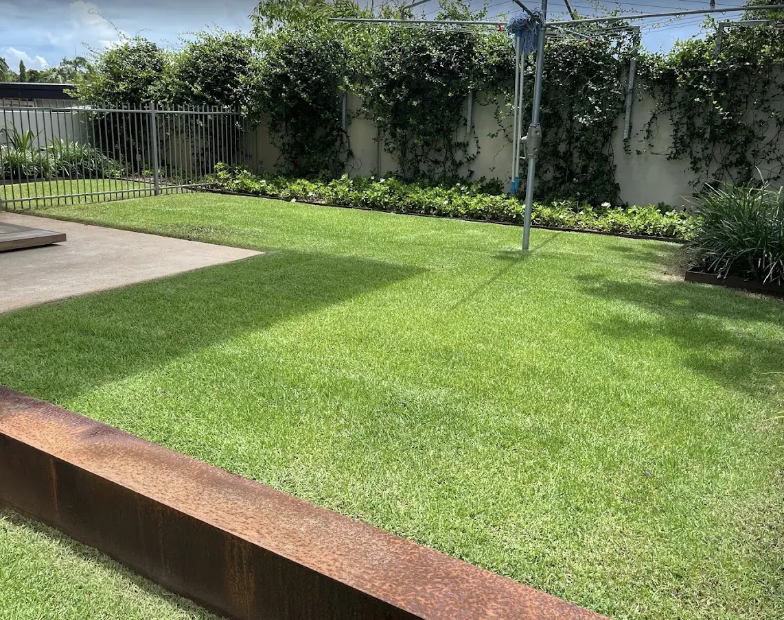 Bright green Harkaway backyard lawn mown and edged around curved garden borders