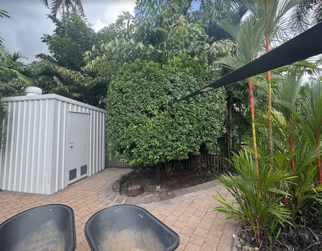 Large rounded hedge trimmed beside a paved Harkaway garden